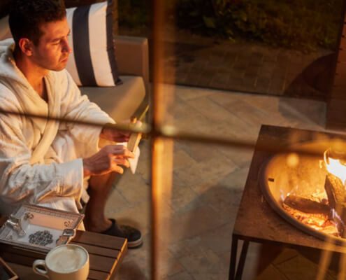 Man in robe drinks coffee in front of the fire - MarriageHeat