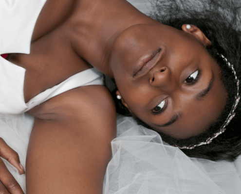 Young black woman in wedding dress relaxing on bed