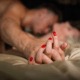 Wife squirms on bed as husband kisses neck and lower. MarriageHeat