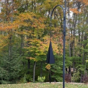 metal wind chimes on a shepard's crook in a backyard setting