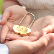heart-shaped lock open in the cupped palms of a husband and wife - MarriageHeat