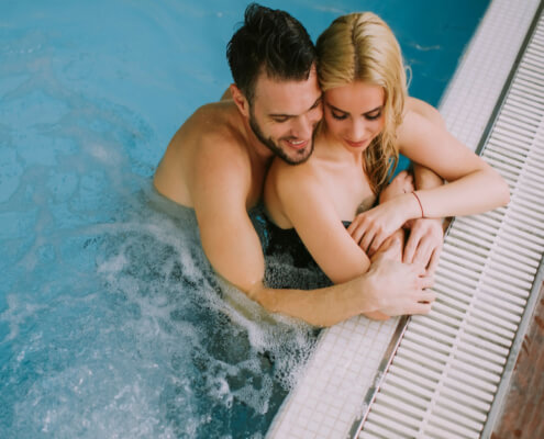 Husband and wife cuddle poolside ~ MarriageHeat