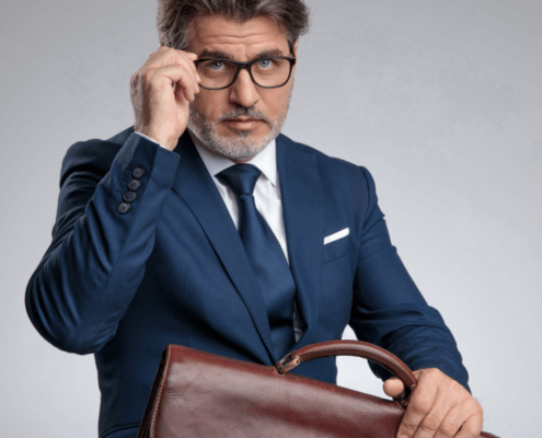 Sexy salesman with leather briefcase adjusts glasses ~ MarriageHeat