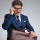 Sexy salesman with leather briefcase adjusts glasses ~ MarriageHeat