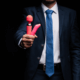 Man's hand holding a pink vibrator ~ MarriageHeat