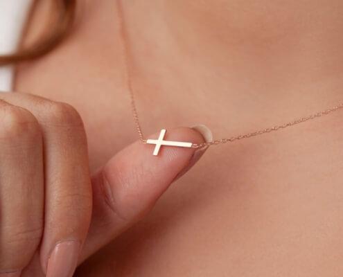 Woman balancing her cross necklace on her thumb - MarriageHeat